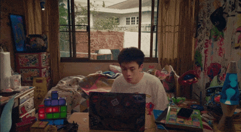a boy sits at a desk with a laptop that has a sticker on it that says ' minecraft ' on it