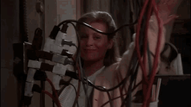 a woman is surrounded by wires and plugged into a wall socket .