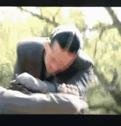 a man in a suit is laying on the ground with his head on his arms .