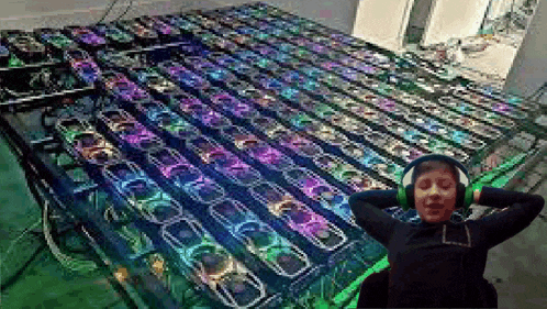 a woman wearing headphones is sitting in front of a table with a lot of computer fans on it .