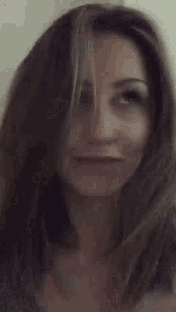 a close up of a woman 's face with long hair and a smile on her face .