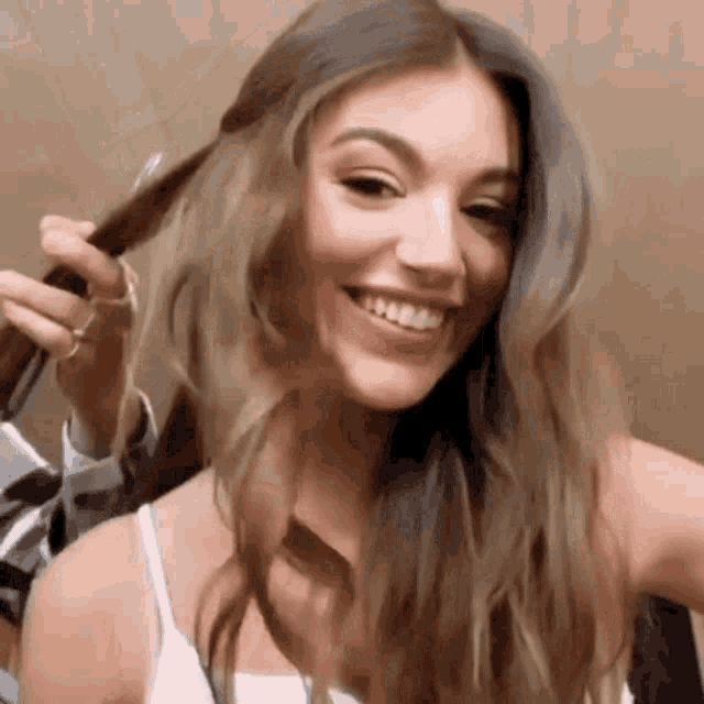 a woman is smiling while holding a brush in her hand .