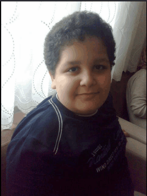 a young boy wearing a wind directory shirt smiles