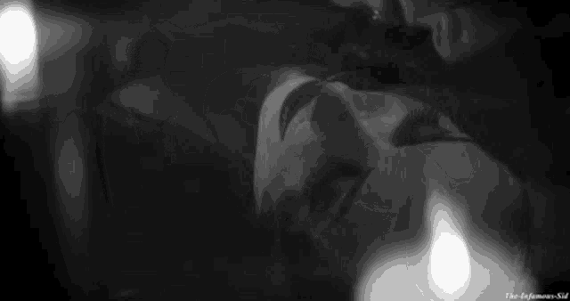 a black and white photo of a woman with a mask on her face next to a candle .