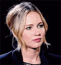a close up of a woman 's face with a black background and a ponytail .