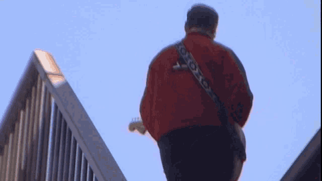 a man in a red jacket playing a white guitar