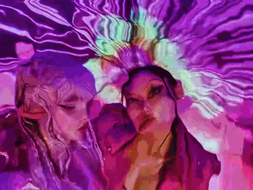 a couple of women standing next to each other in front of a purple background .
