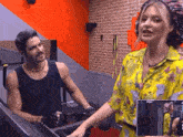 a woman in a yellow shirt is standing next to a man on a treadmill .