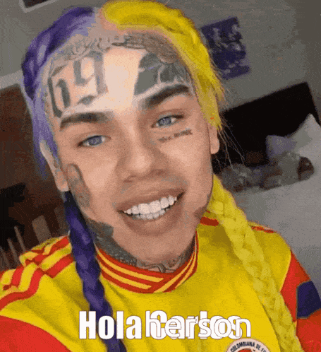 a man with purple and yellow hair is wearing a yellow and red jersey that says hola harson