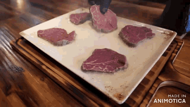 a white plate with four pieces of meat on it is made in animatica