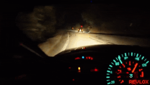 a person is driving a car at night and the speedometer shows that they are going very fast .