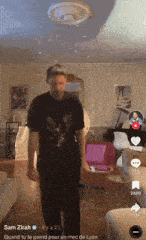 a man wearing a black shirt with an eagle on it is dancing in a living room