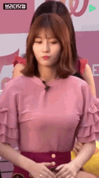 a woman in a pink shirt and red shorts is standing with her hands on her stomach .