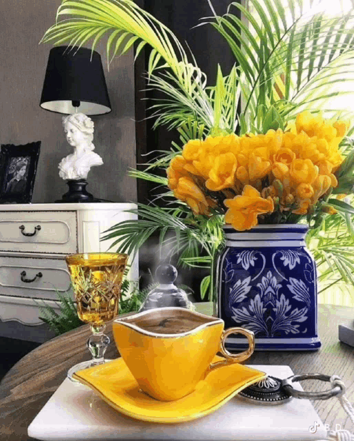 a vase of yellow flowers sits next to a cup of coffee