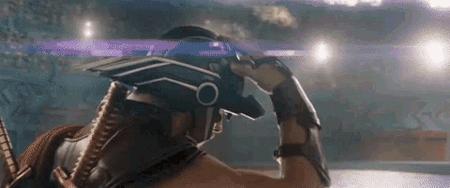 a man wearing a helmet is standing in a stadium and looking at something .