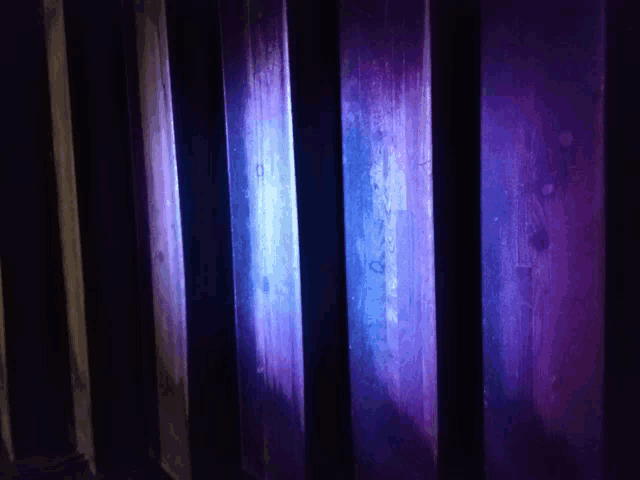 purple and blue lights are shining on a dark wooden surface