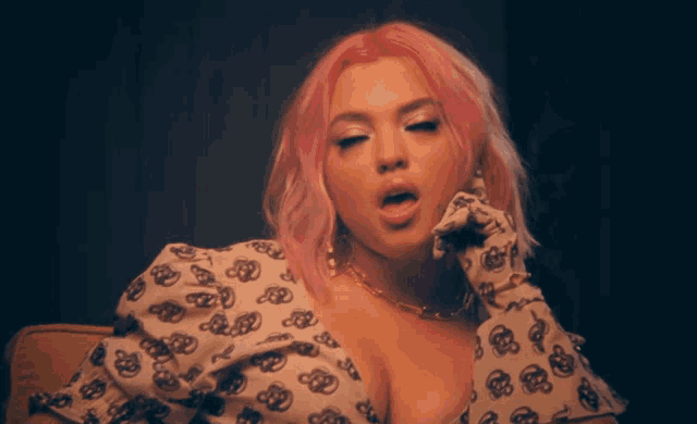 a woman with pink hair is wearing a white shirt with skulls on the sleeves