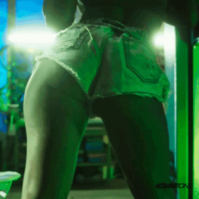 a woman in shorts is standing in front of a green sign that says gato on it