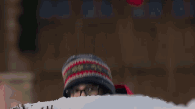 a person wearing a hat and scarf is being covered in snow .