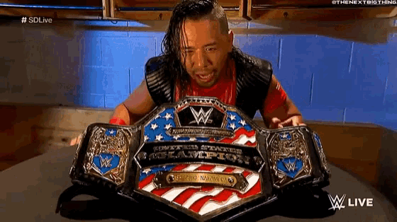 a wrestler is holding a wwe world heavyweight championship belt on a table .