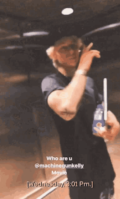 a man in a black shirt is holding a bottle of pepsi and talking on a cell phone