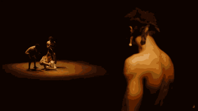 a man without a shirt is standing in front of a group of people in a dark room