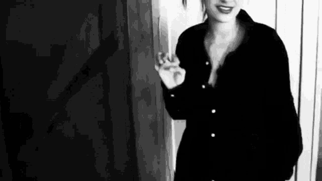 a black and white photo of a woman smoking a cigarette in a room .