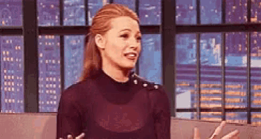 a woman is standing in front of a window while talking on a television show .