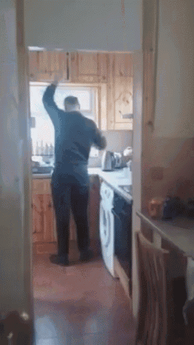 a man is standing in a kitchen with his arms up