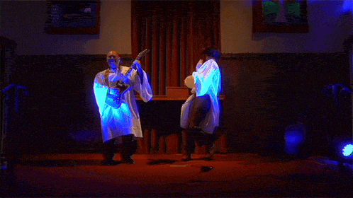 a man in a lab coat is playing a guitar and a man in a white robe is playing a drum