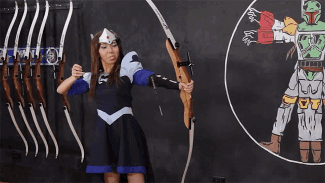 a woman is holding a bow and arrow in front of a boba fett drawing on a blackboard