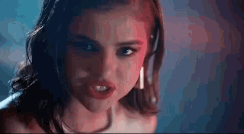 a close up of a woman making a funny face with her mouth open in a dark room .