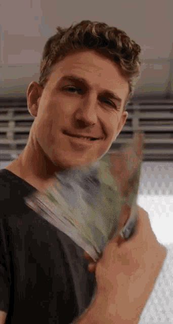 a man in a black shirt is holding a stack of money in his hand