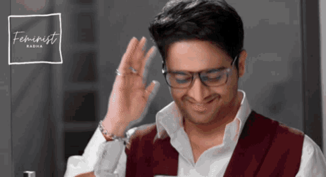 a man wearing glasses is smiling in front of a feminist logo