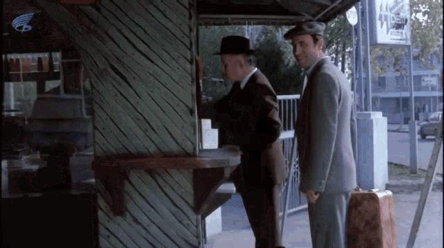 two men are standing in front of a sign that says ' a '