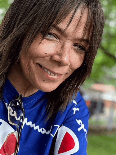 a woman wearing a blue champion shirt is smiling for the camera