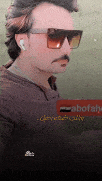 a man wearing sunglasses is standing in front of a sign that says abofahe