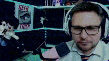 a man wearing glasses and headphones is sitting in front of a sign that says geek trick .