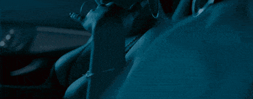 a man wearing sunglasses and a hat is sitting in a dark room with two women