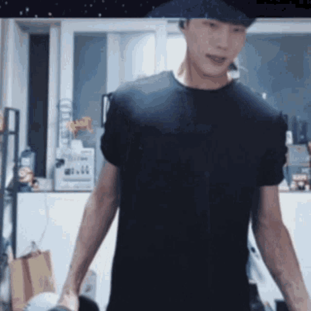 a man in a black t-shirt is standing in a kitchen