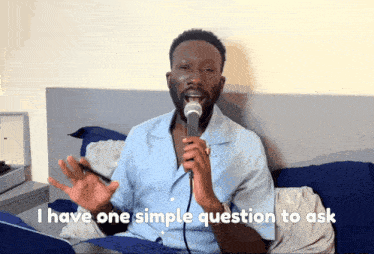 a man singing into a microphone with the words i have one simple question to ask behind him