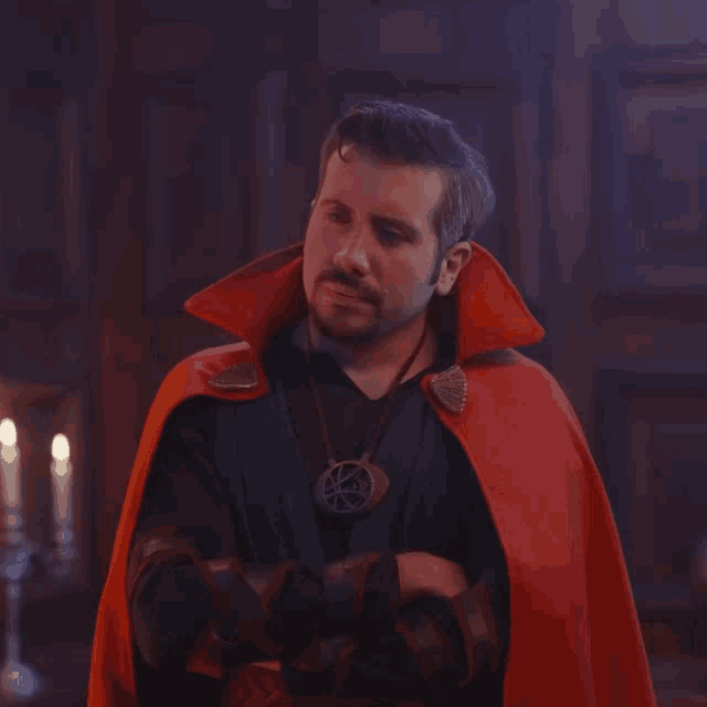 a man in a doctor strange costume stands with his arms crossed in a dark room