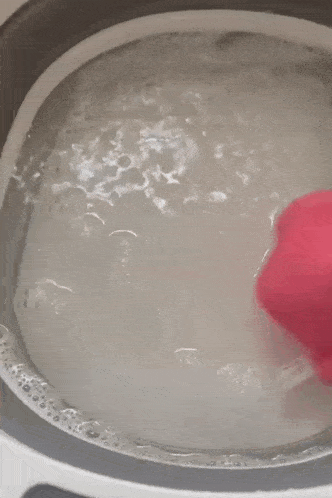 a pink heart is floating in a pot of water
