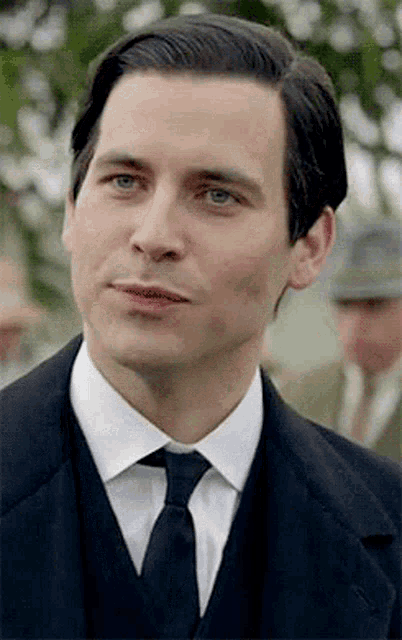 a man in a suit and tie is looking at the camera