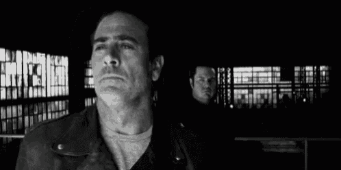 a black and white photo of a man in a leather jacket standing next to another man .