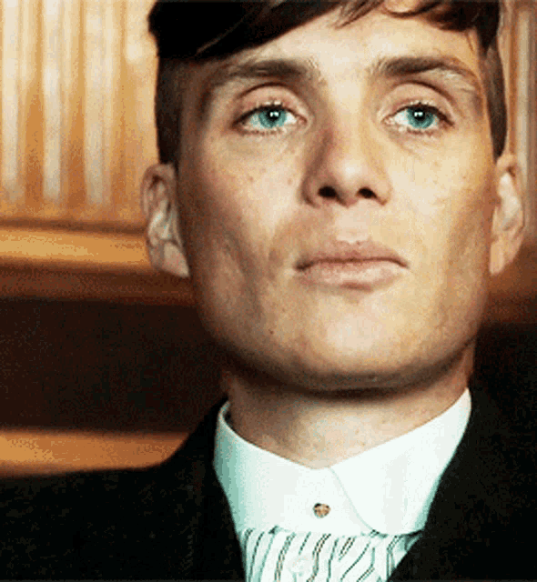 a close up of a man 's face with a white shirt and tie
