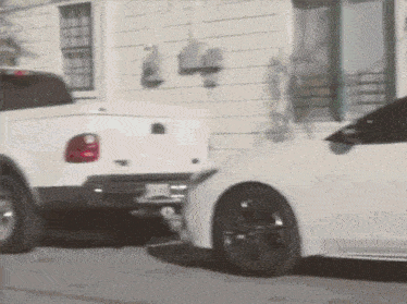 a white truck and a white car are parked in front of a white house