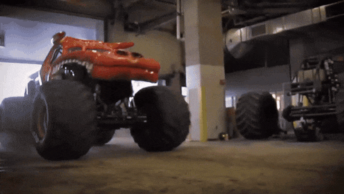 a monster truck is driving through a garage with a large tire on the ground