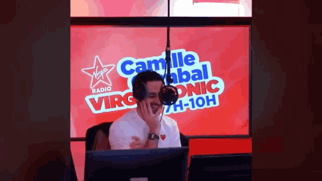 a man is sitting in front of a microphone in front of a virgin radio sign