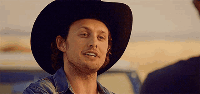 a man wearing a black cowboy hat and denim shirt
